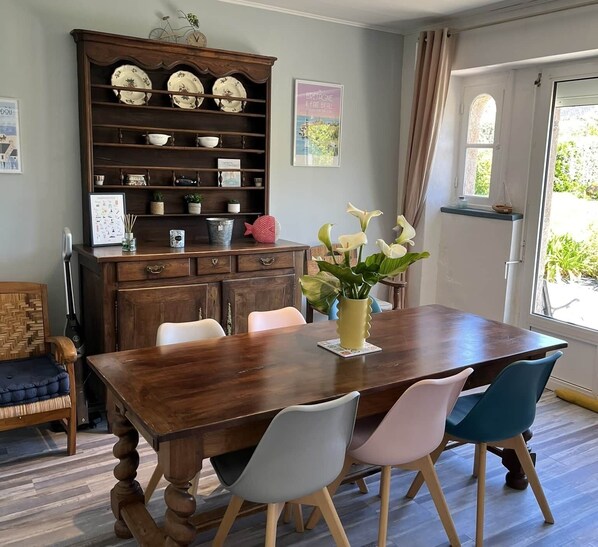 Un comedor con una mesa de madera, sillas, un aparador decorativo y un florero con flores.