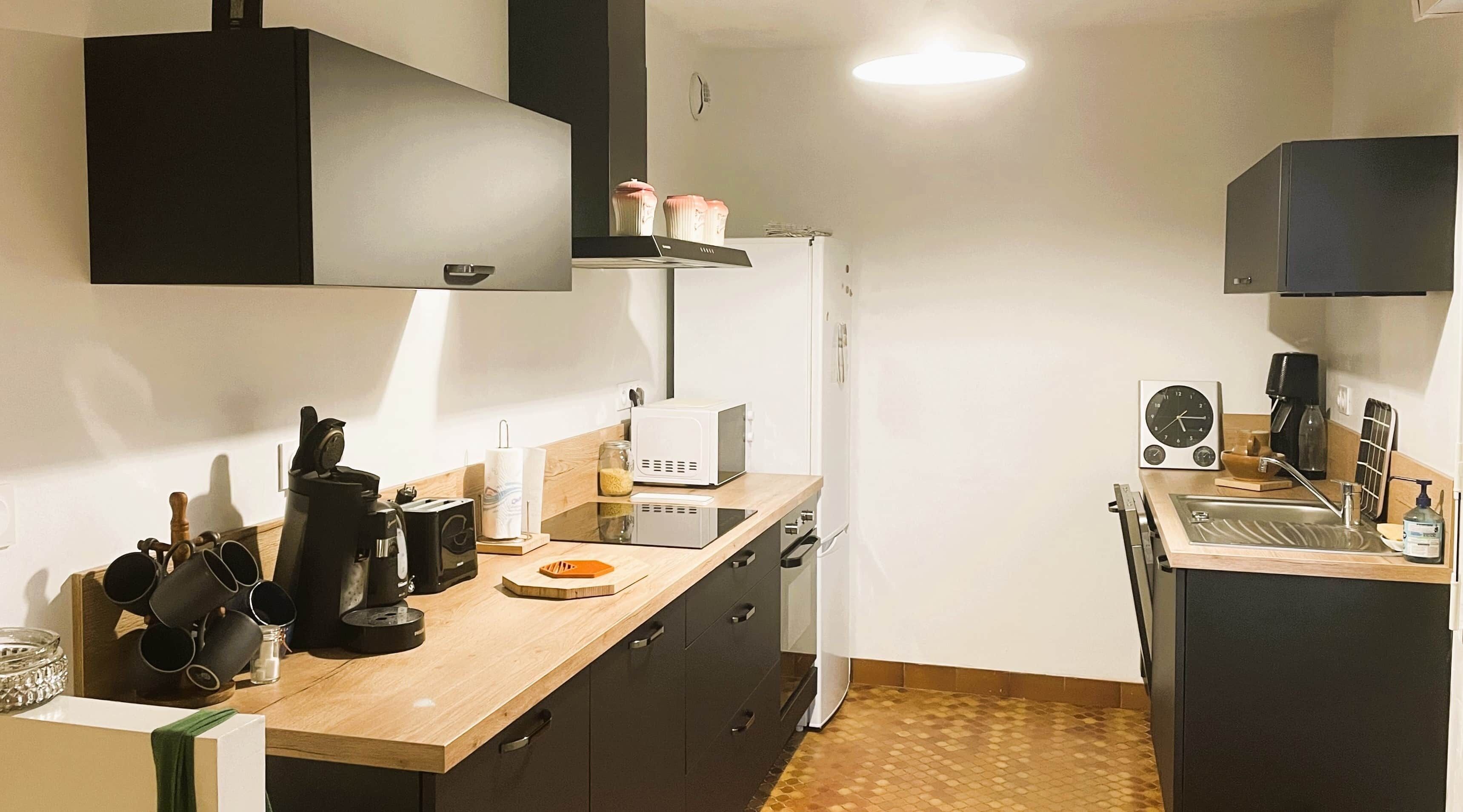 A compact kitchen with a microwave, toaster, and coffee maker on the counter, a sink, and a refrigerator.