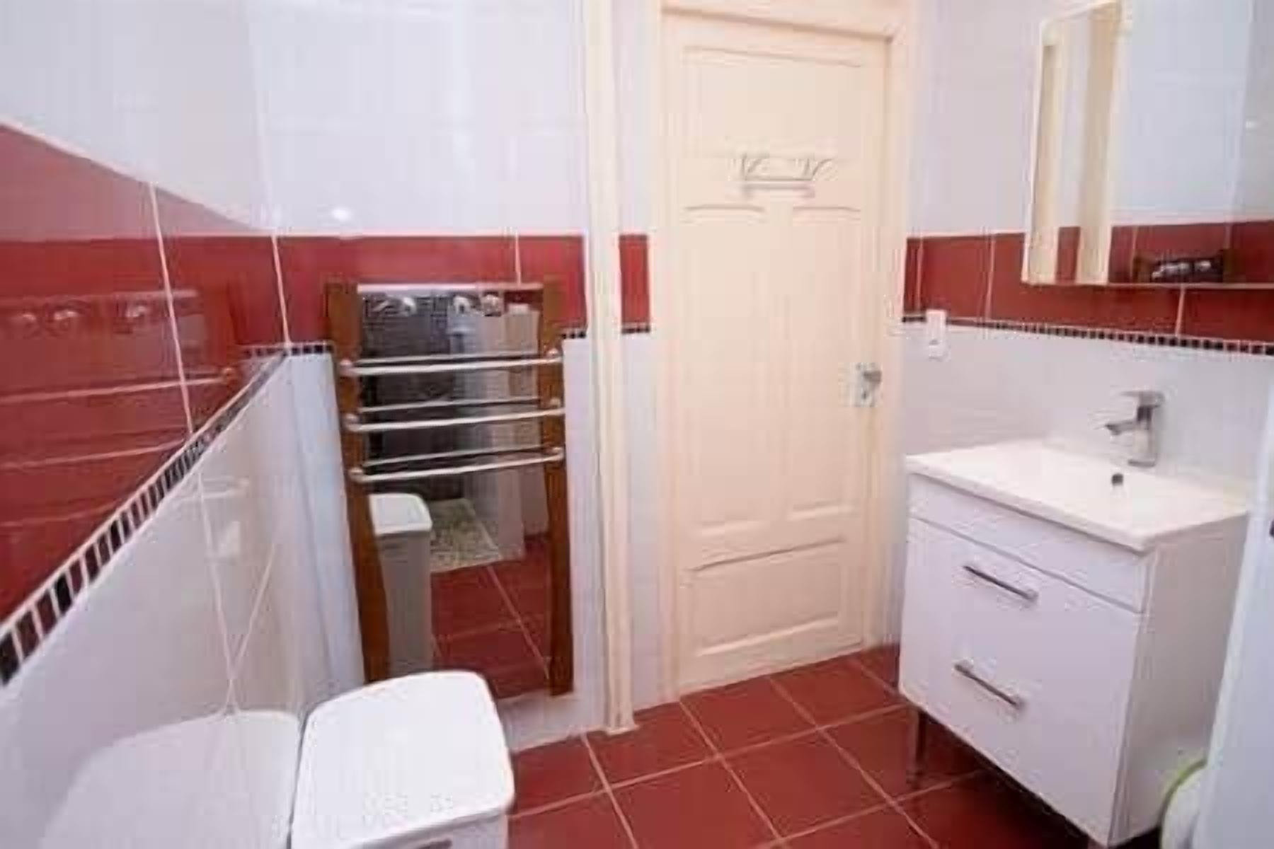 A bathroom with a white sink, a mirror, a towel rack, and a door.