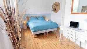 A bedroom with a bed, bedside table, and a desk with a laptop. - Gevelled, Town house Perros (Perros-Guirec)