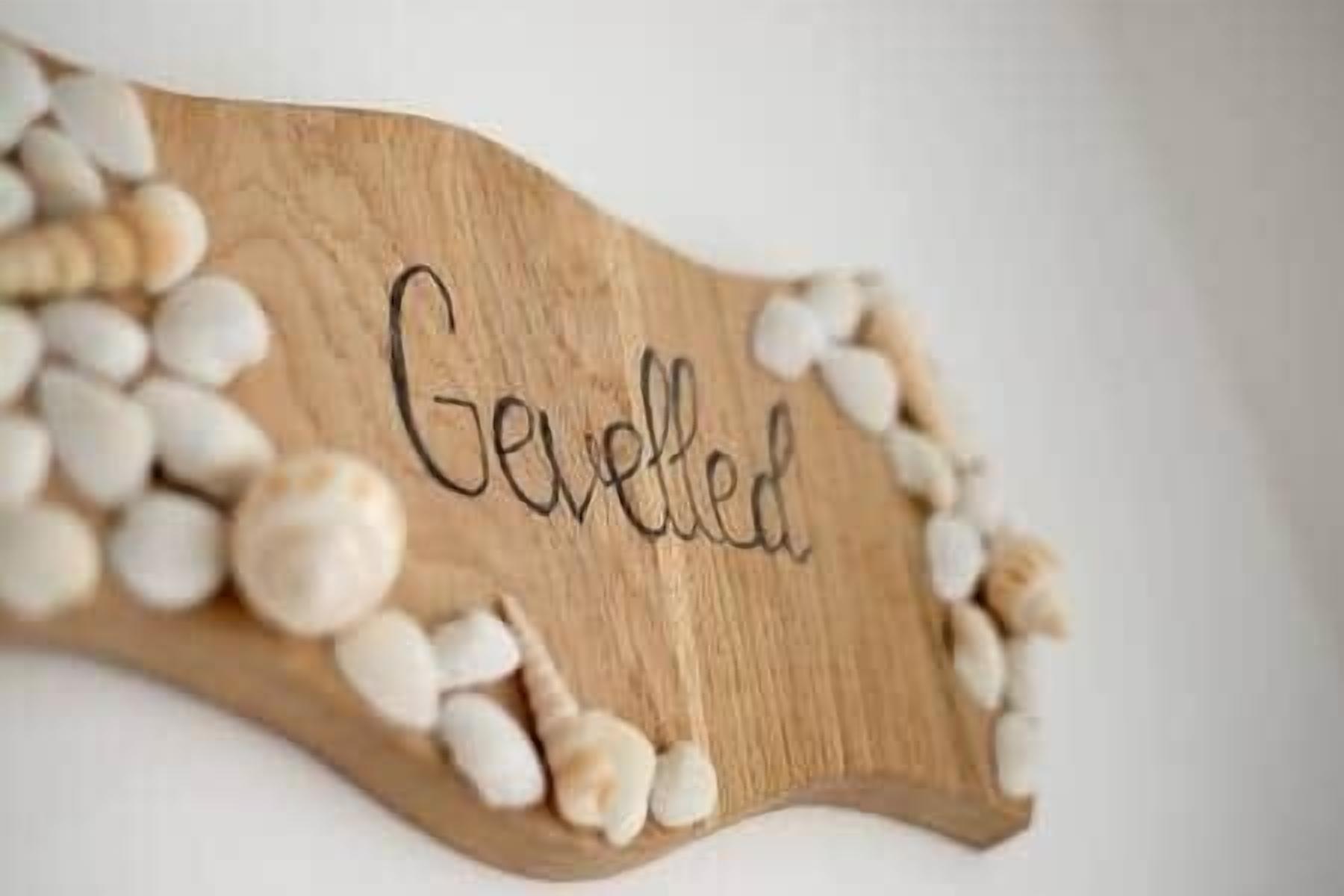 A wooden sign with the word "Gevled" surrounded by white pebbles.