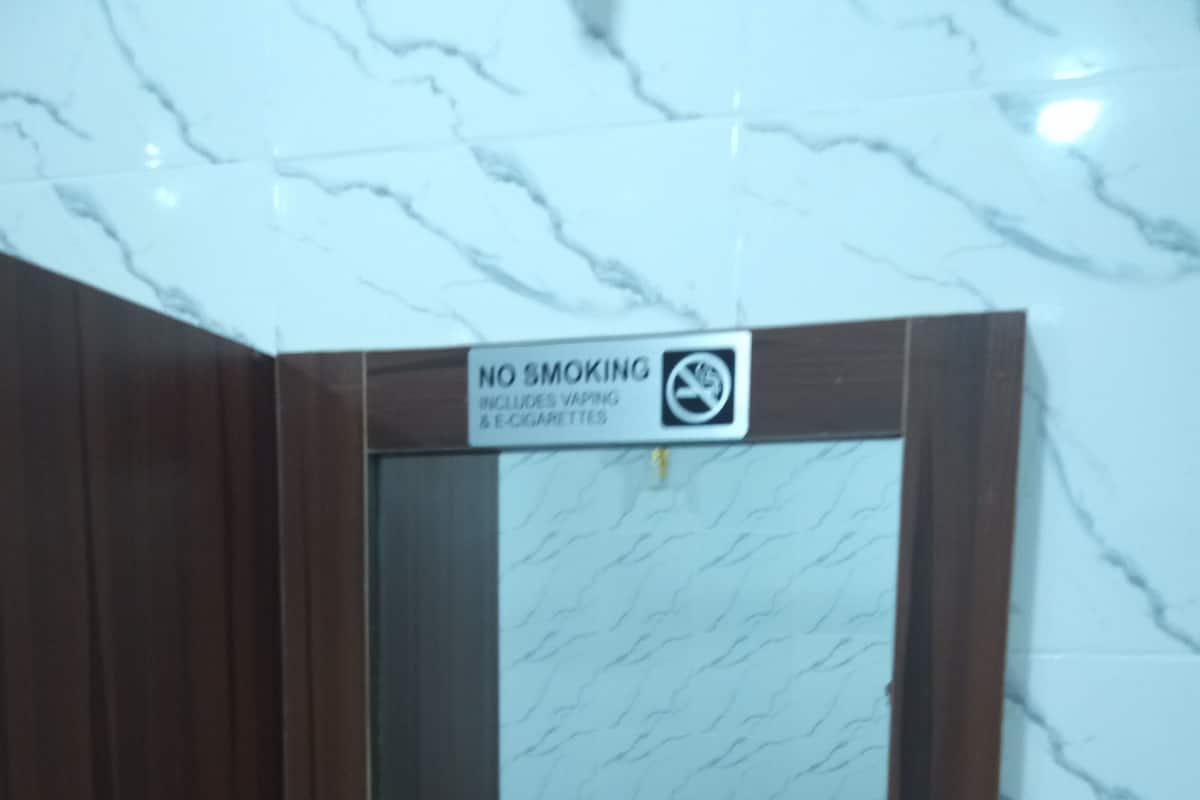 Ein Rauchverbot-Schild über einem Spiegel, der einen Raum mit einer Couch und einem Tisch reflektiert.