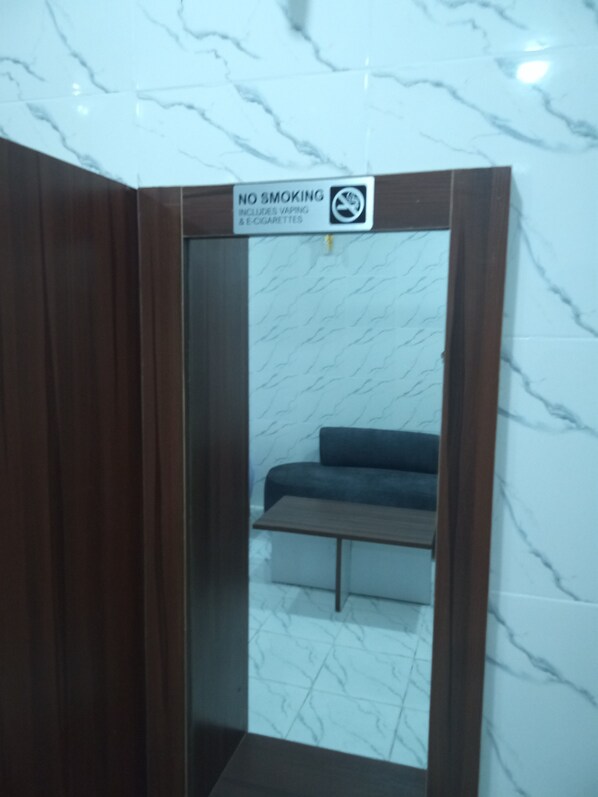 A no-smoking sign above a mirror reflecting a room with a sofa and a table. - Wiings Hotel & Banquet (Uyo)