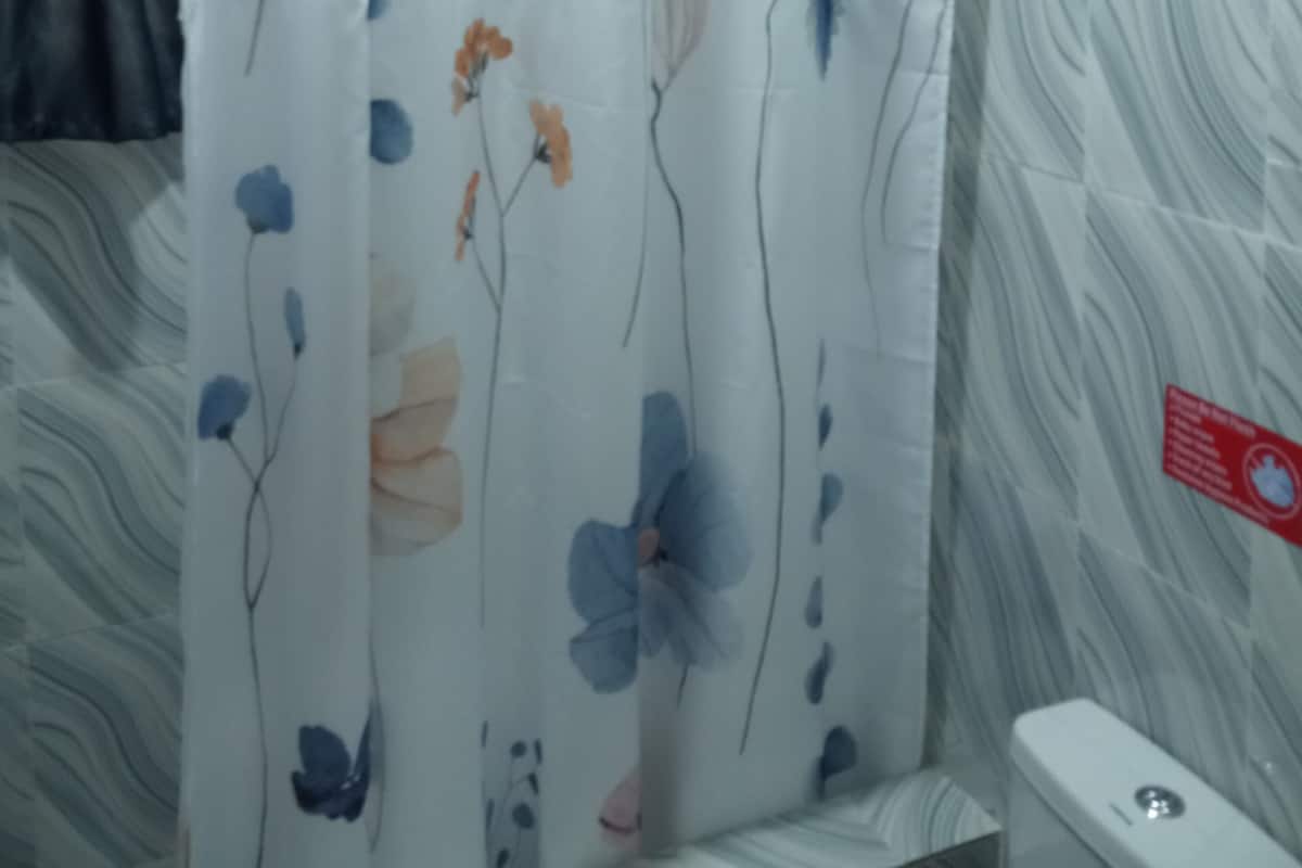 Ein Badezimmer mit Duschvorhang mit Blumenmuster, einem Handtuchhalter und einer Toilette.