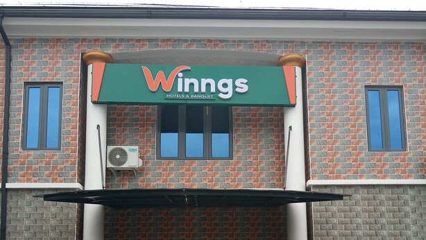 Un bâtiment sur lequel on peut lire l’inscription « Winngs Hotels & Banquet » et, au-dessus de l’entrée, une autre inscription indiquant « Salle de réception ».