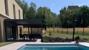 Una piscina rectangular con agua azul cristalina, rodeada por una solana con baldosas.