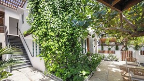 Un patio con escaleras, valla blanca y zona de estar con sillas.