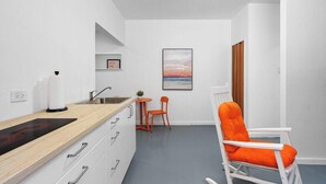 A compact kitchen with a wooden countertop, a sink, and a small table with a chair.