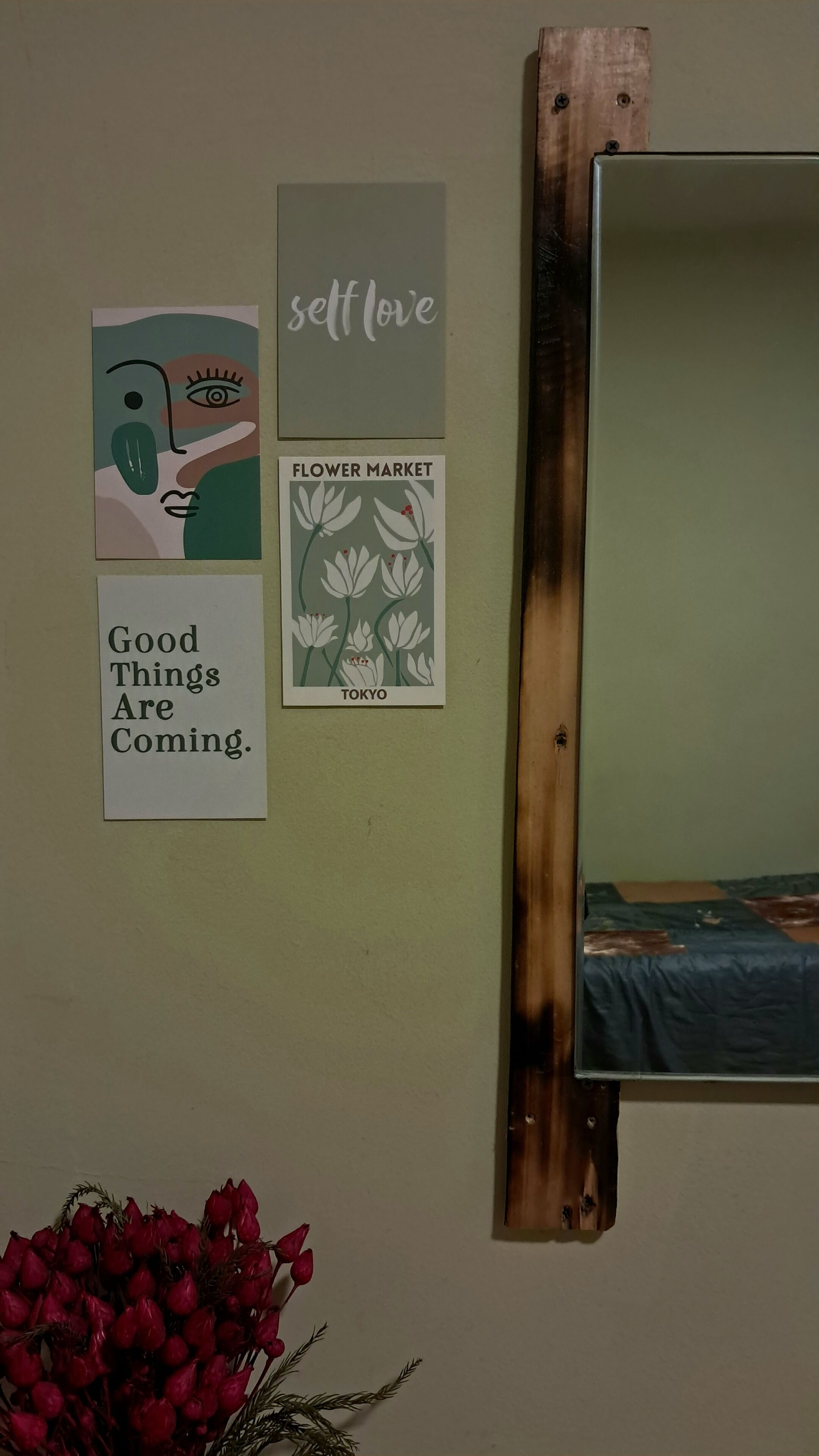 A wall with three framed items: a painting, a sign with 'self love', and a sign with 'flower market TOKYO'.