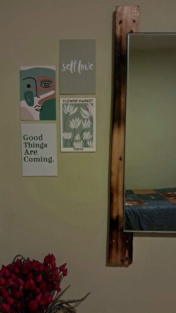 A wall with three framed items: a painting, a sign with 'self love', and a sign with 'flower market TOKYO'.