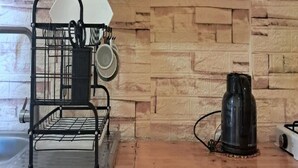 Una cocina con estantes de madera que sostienen frascos y un hervidor.