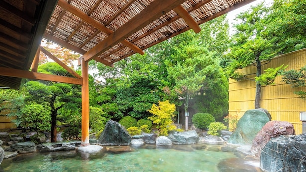 Egy hagyományos japán onsen, melynek jellemzője a tiszta, forró termálvíz, a fagerendák és a buja zöld növényzet.