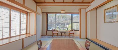Una habitación japonesa tradicional con suelo de tatami, una mesa baja y puertas correderas.