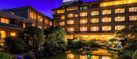 A hotel with a reflection pool, multiple floors, and a sign in Japanese.