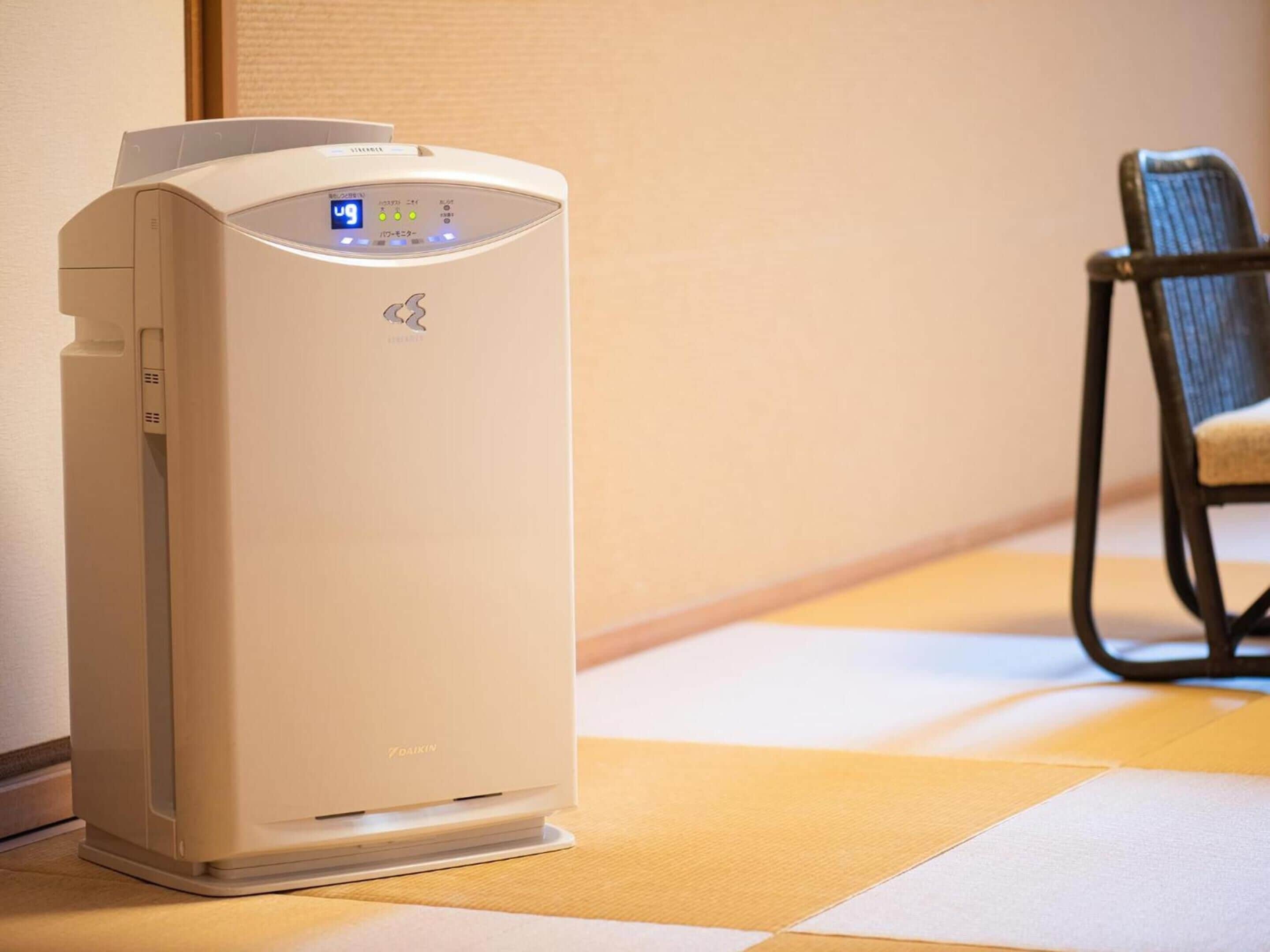 A portable air conditioner with a digital display, placed on a checkered floor near a chair.