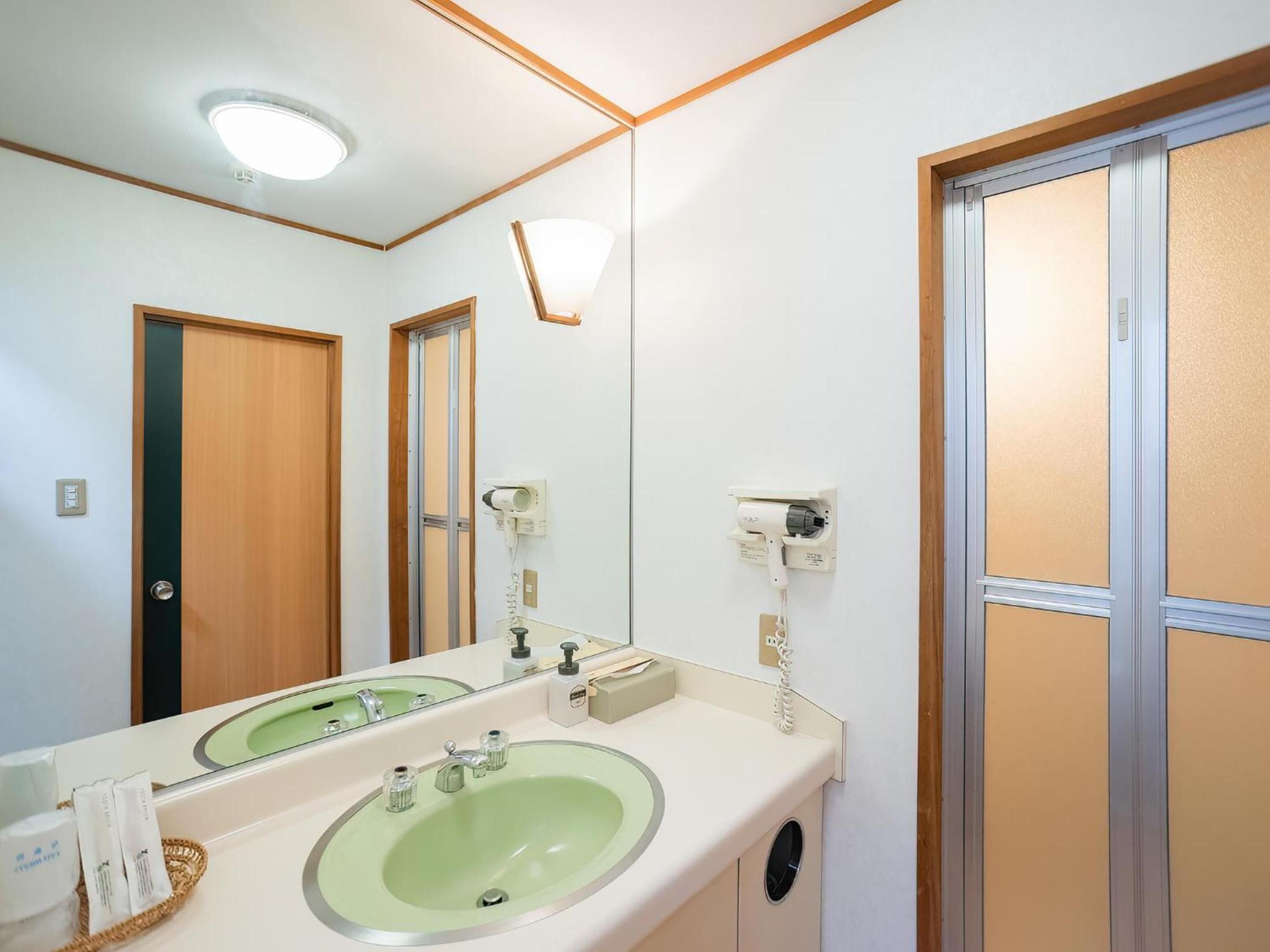 Ein Badezimmer mit zwei Waschbecken, einem Spiegel, einem Fön und einem Telefon.