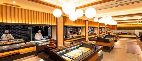 Un restaurante moderno con una barra central que exhibe diversos alimentos, rodeado de paneles de madera e iluminación colgante.