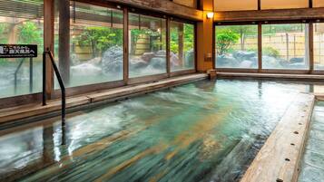 Un onsen japonais traditionnel, doté d’une terrasse en bois et de grandes fenêtres donnant sur un jardin.