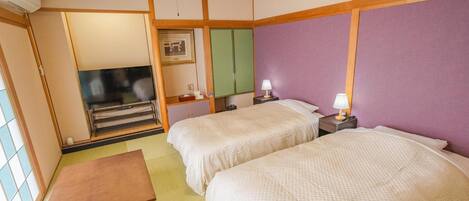 Habitación de hotel con dos camas, televisión, escritorio y ventana.