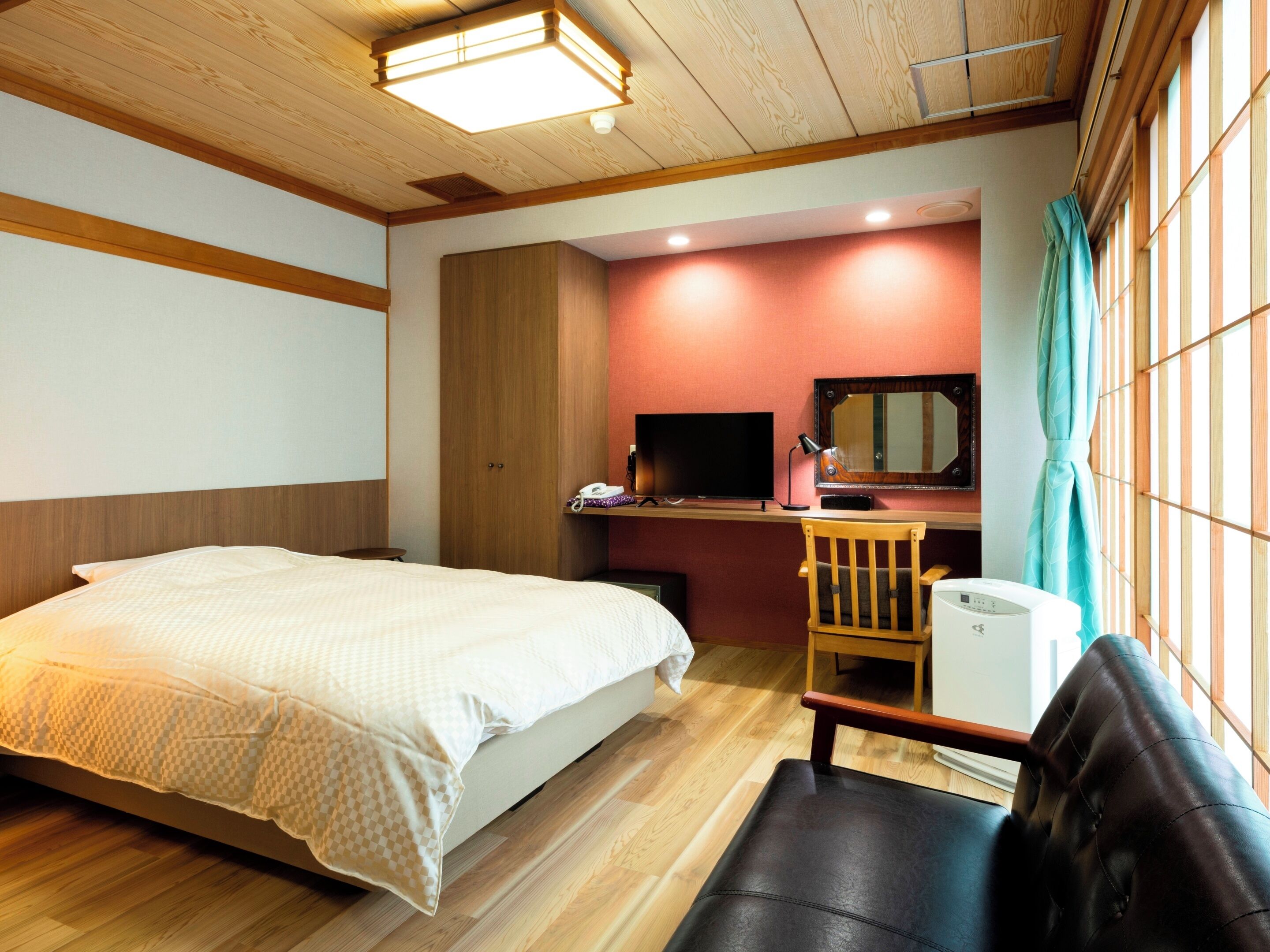Ein Hotelzimmer mit Bett, Schreibtisch, Stuhl und Fernseher.
