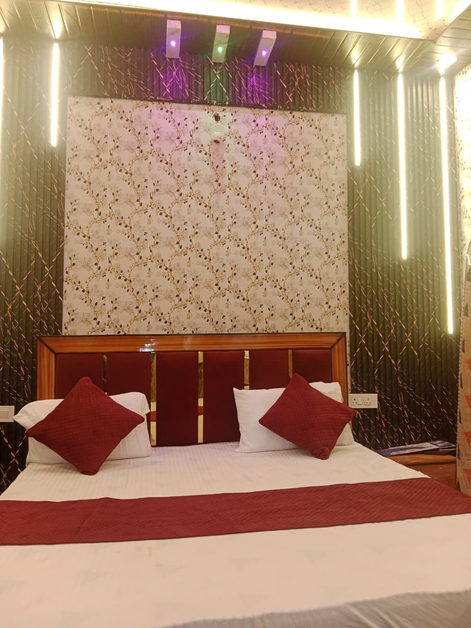 Ein Hotelzimmer mit einem großen Bett, einem hölzernen Kopfteil und einer Wand mit floralem Muster.