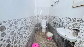 A bathroom with patterned walls, a toilet, a sink, and a bucket.