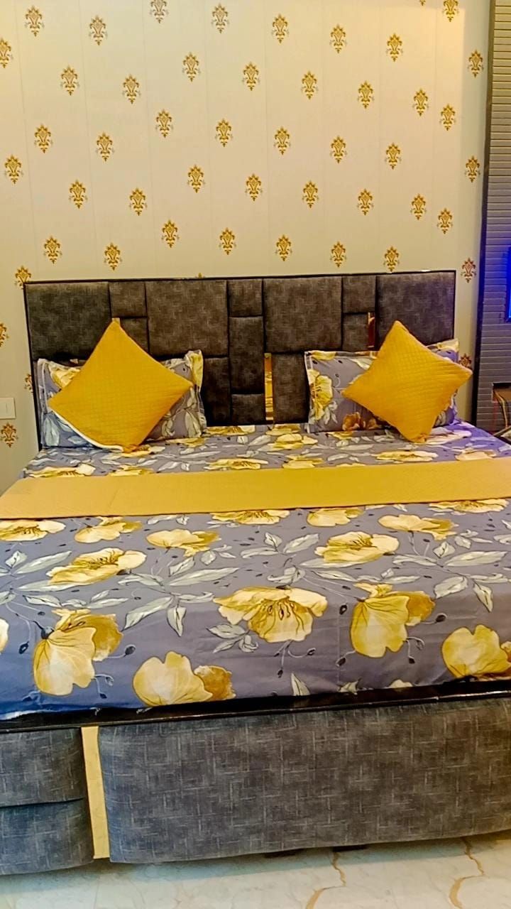 A bed with a floral bedspread, two pillows, and a headboard with a patterned wallpaper background.