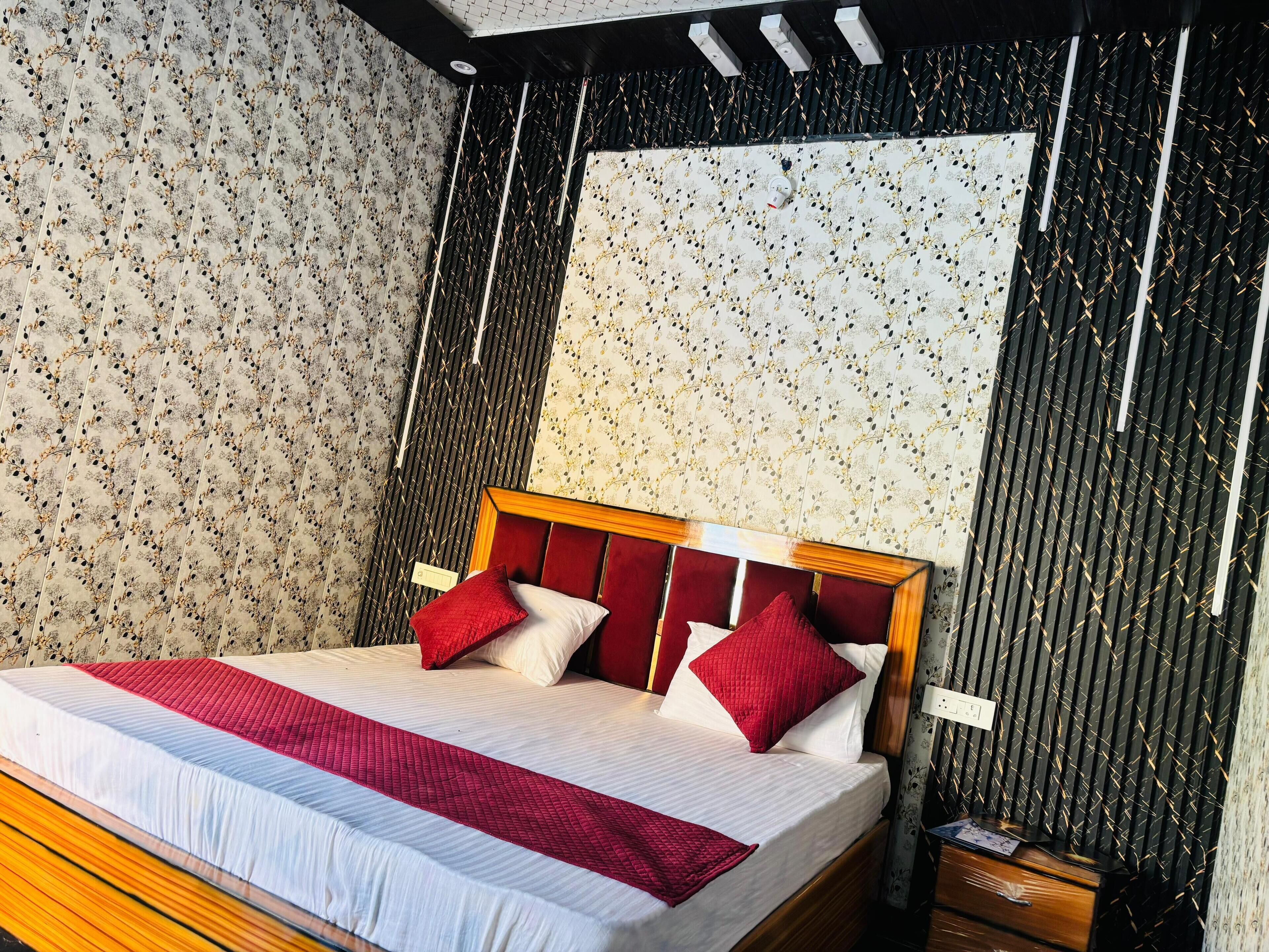 Un lit bien fait, avec une tête de lit en bois, une literie rouge et blanche, et un plaid rouge.