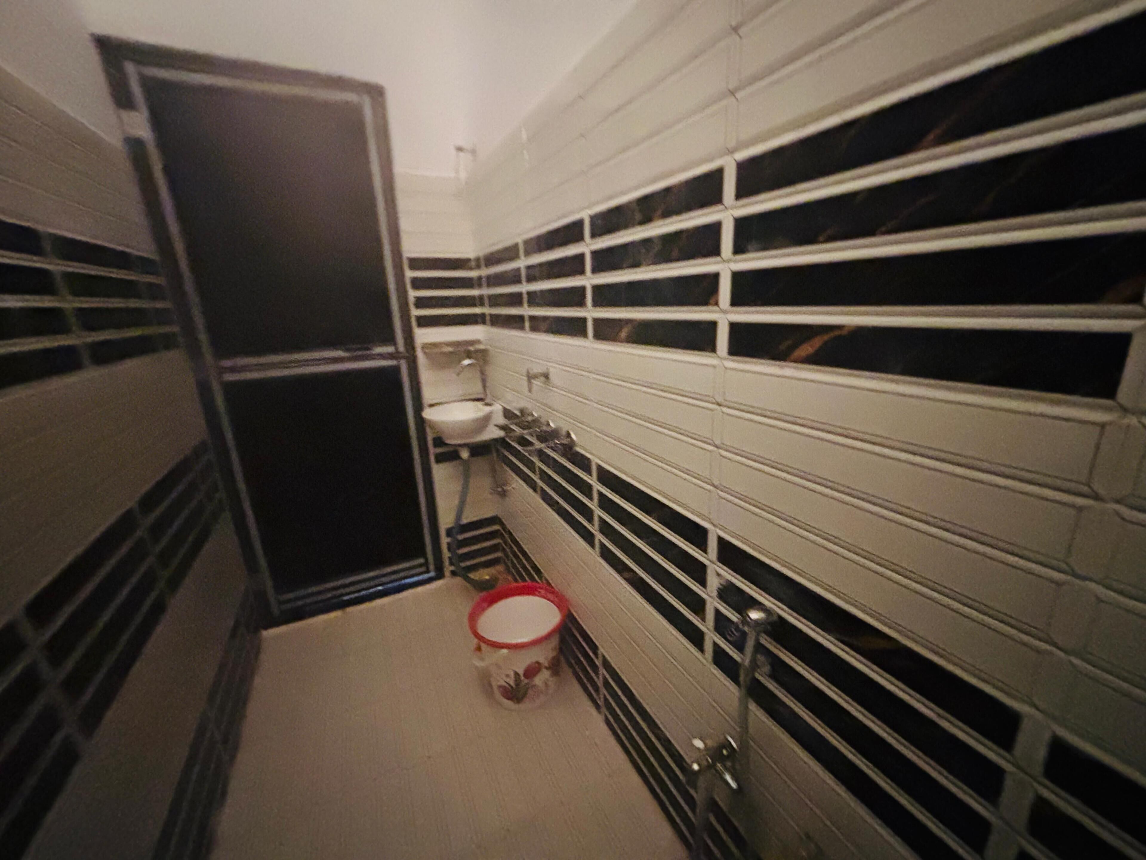 A narrow bathroom with a toilet, sink, and a metal rack for storage.