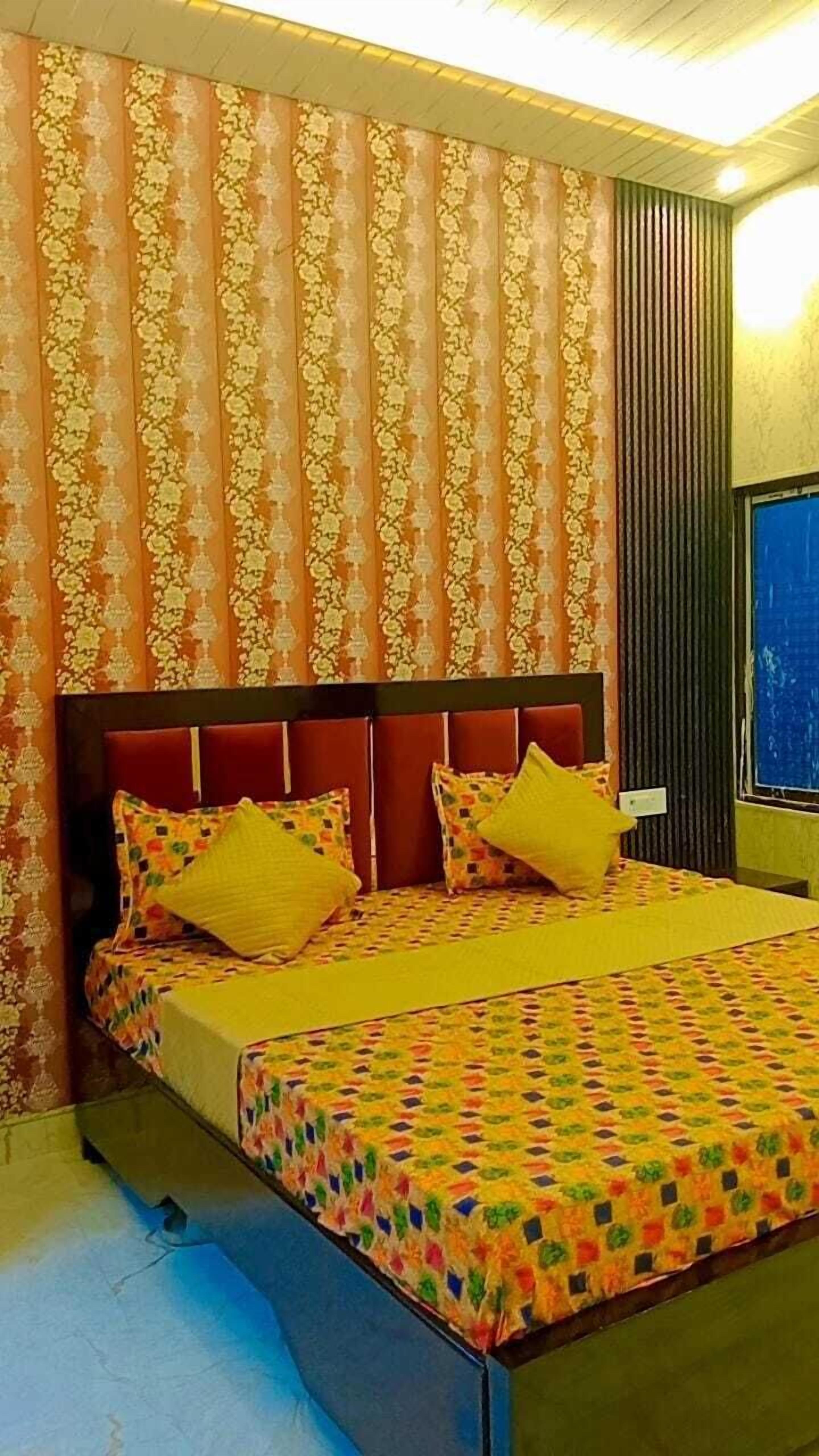 A bedroom with a patterned wallpaper, a wooden headboard, and a bed with a colorful quilt.