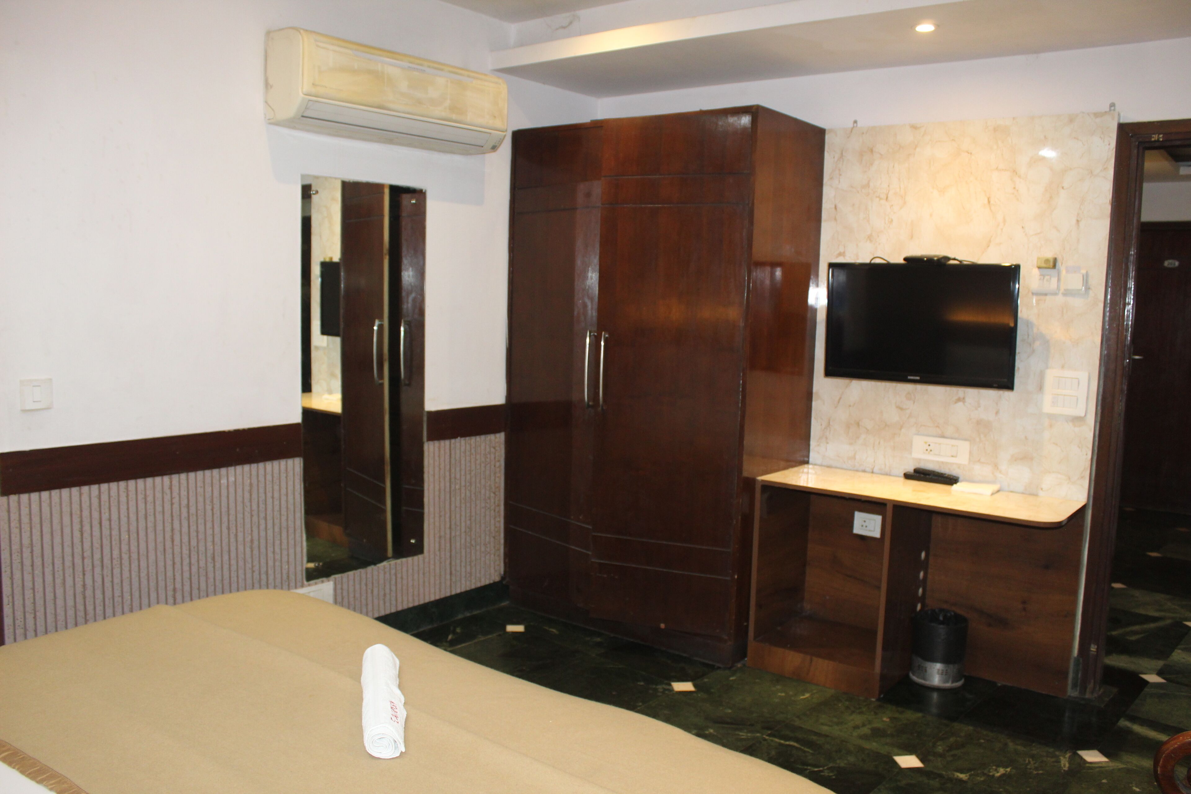 Une chambre d’hôtel comprenant un lit, une coiffeuse avec un miroir, une télévision et une armoire.