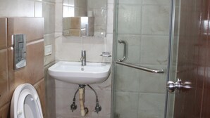 A bathroom with a toilet, sink, and glass-enclosed shower. - Flourish Inn Saket opposite Max Hospital (New Delhi)