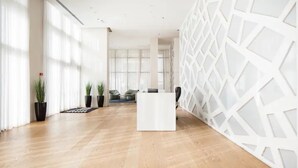 A spacious lobby with a reception desk, wooden flooring, large windows, and potted plants. - Special Apartment Sea View Luxury Tower (Bat Yam)