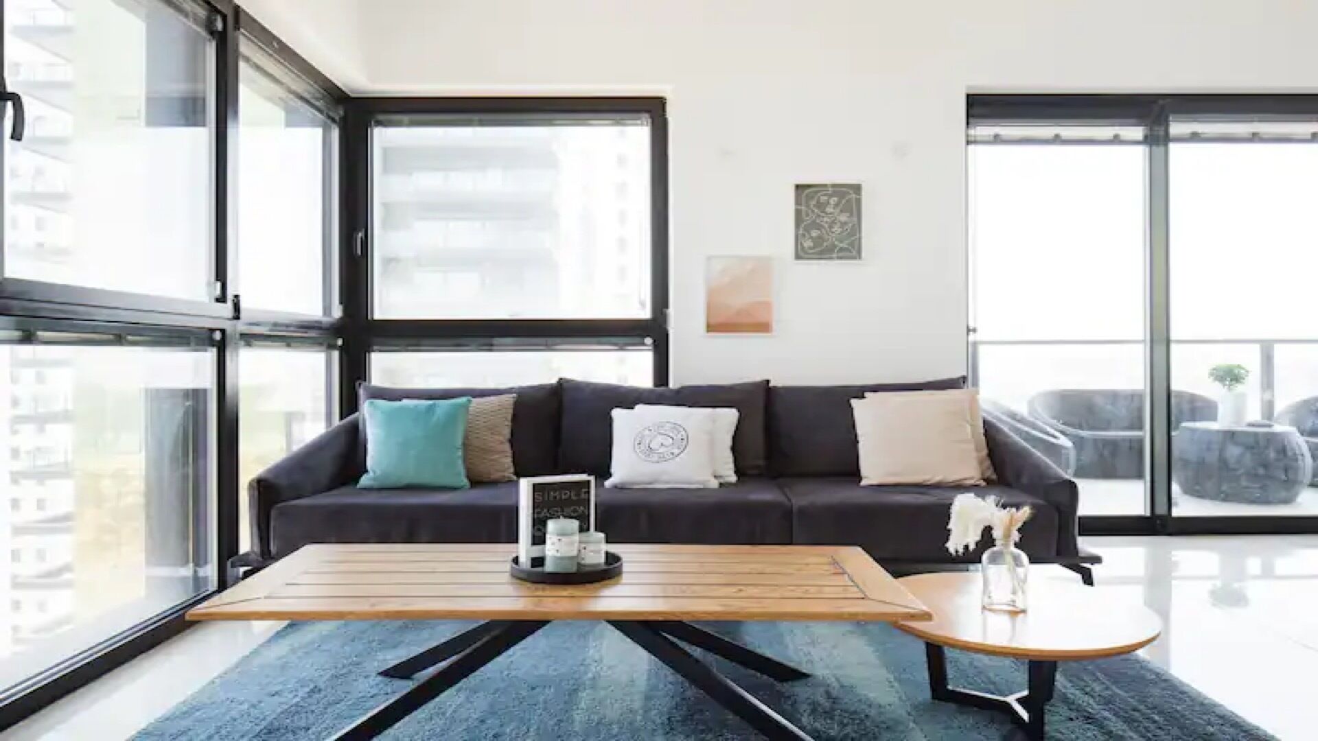 A modern living room with a dark-colored sofa, a wooden coffee table, and a blue rug.