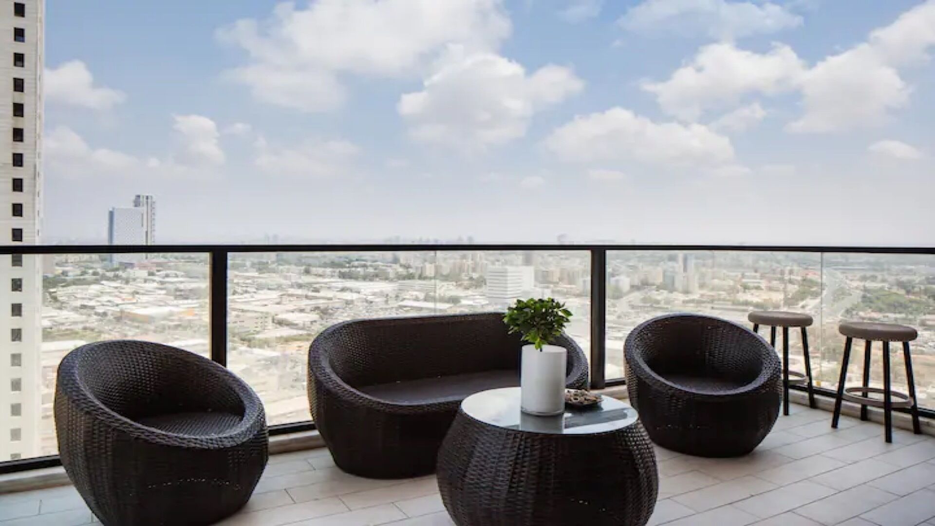 A balcony with wicker furniture, a small table, and a potted plant.