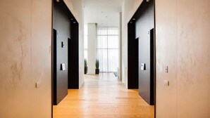 A modern hallway with wooden flooring and black walls, leading to a bright room with large windows. - Special Apartment Sea View Luxury Tower (Bat Yam)