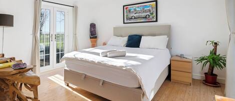 Una camera da letto con un letto, comodino, tavolo da notte e una pianta in vaso.