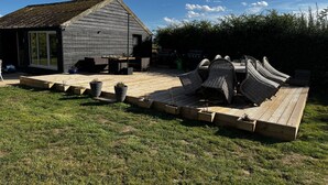 A wooden deck with outdoor furniture and a grill area. - Guys Head Cottage (Spalding)