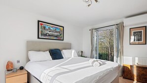 A bedroom with a bed, a nightstand, a window with a view, and a framed picture on the wall. - Guys Head Cottage (Spalding)