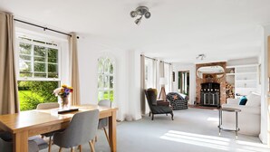 A spacious living area with a dining table, chairs, a fireplace, and a sofa. - Guys Head Cottage (Spalding)