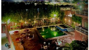 A rooftop pool area with outdoor seating and a view of the city at night. - Umraogarh A Unit of Raghav Vilas (Jodhpur)