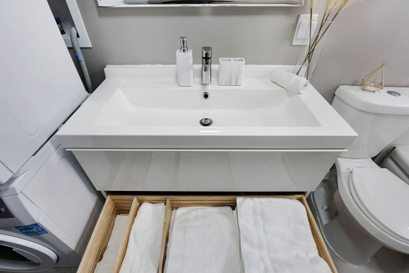 Ein modernes Badezimmer mit einem großen weißen Waschbecken, einer Toilette und einem hölzernen Handtuchhalter.