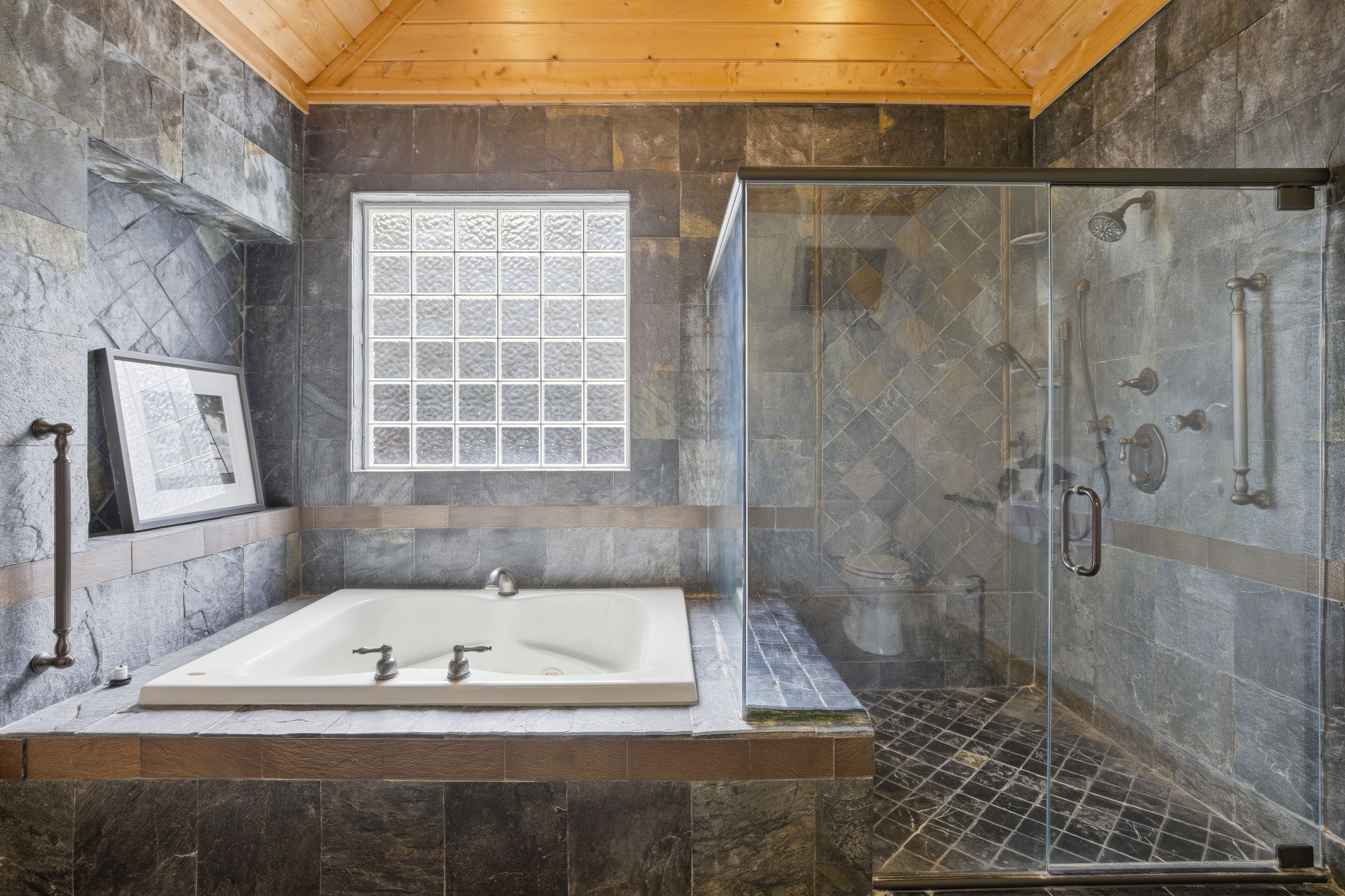 A bathroom with a large bathtub, a glass-enclosed shower, and a window with a decorative grid pattern.