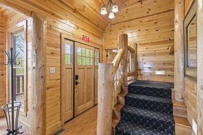 A wooden interior with an exit sign, a staircase, and a door with windows. - Lodge with Fire Pit, Indoor and Outdoor Fireplace, Hot Tub, Games, King Beds (Sevierville)
