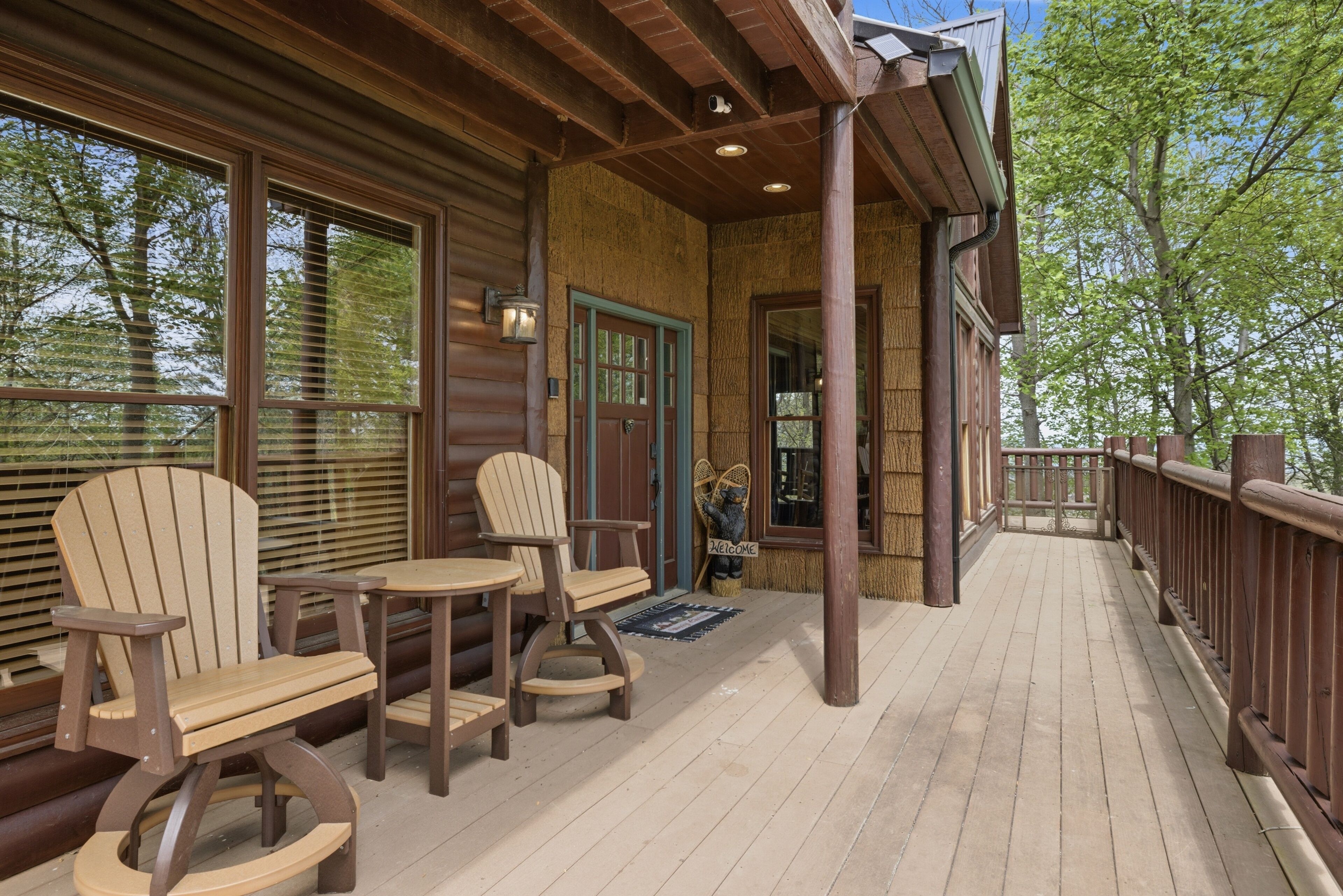 A wooden deck with Adirondack chairs and a welcome mat.