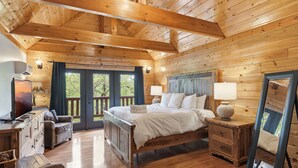 Ein Schlafzimmer einer Holzhütte mit Bett, Schminktisch und großem Spiegel.