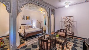 Una habitación con cama, una silla, una mesa y un arco decorativo.
