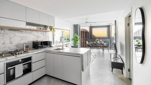 Een moderne keuken met een marmeren aanrechtblad, inbouwapparatuur en een groot kookeiland.