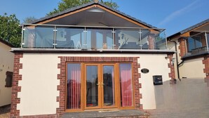 Un immeuble de deux étages doté d’un balcon, de grandes portes vitrées et d’une façade en briques.