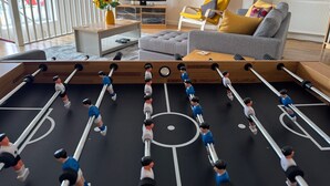 Un salon avec une table de baby-foot, un canapé, un téléviseur et un balcon offrant une vue agréable.